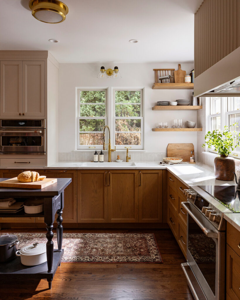 Stained oak cabinetry and floating shelves above the sink in a Whitefish Bay kitchen remodel